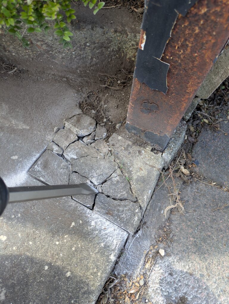 Using an SDS to carefully break concrete to remove an old gate post
