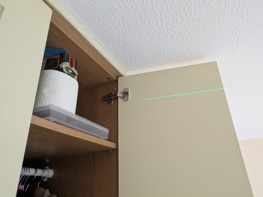 Using a toilet roll to prop up a laser level for ensuring the curtain rail we were fitting was level and centered